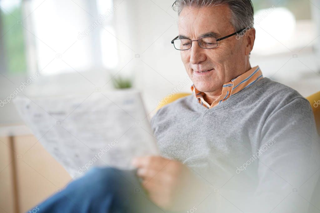  man with eyeglasses reading newspaper