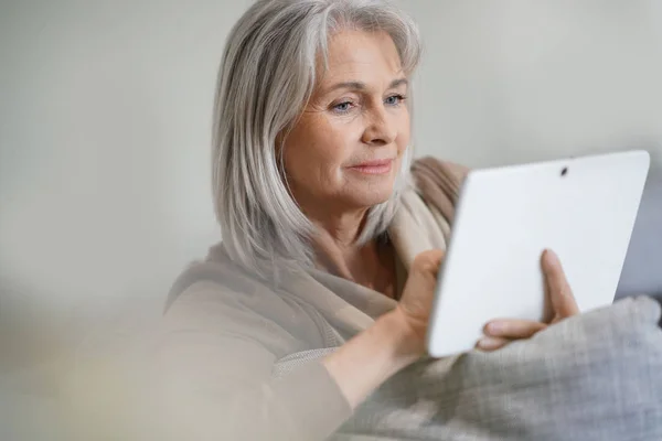 Starszy kobieta podłączony na cyfrowy tablicowy — Zdjęcie stockowe