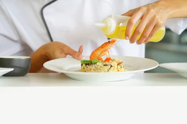 Chef hand sprinkling oil on dish — Stock Photo, Image