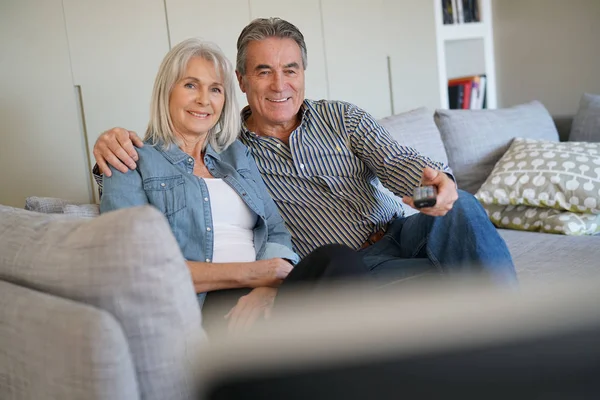 Couple sitting in couch watching tv — Stock Photo, Image