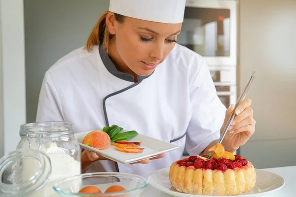 Pastry chef decorating raspberry cake — Stock Photo, Image