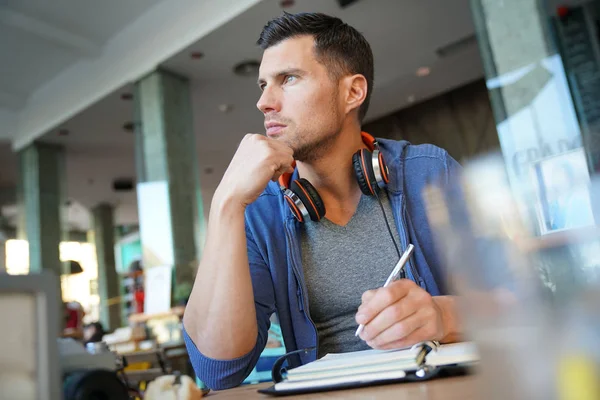 Homme assis au restaurant écrivant des notes — Photo