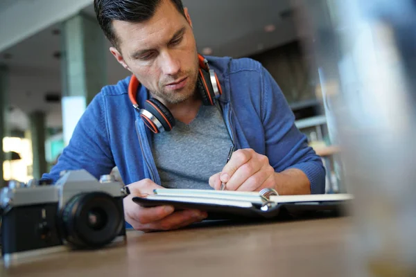 Hombre sentado en el restaurante escribiendo notas —  Fotos de Stock