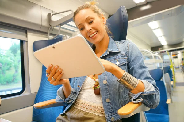 Женщина в поезде подключена на планшете — стоковое фото