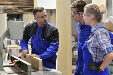 Atölyede çırakları olan marangoz.