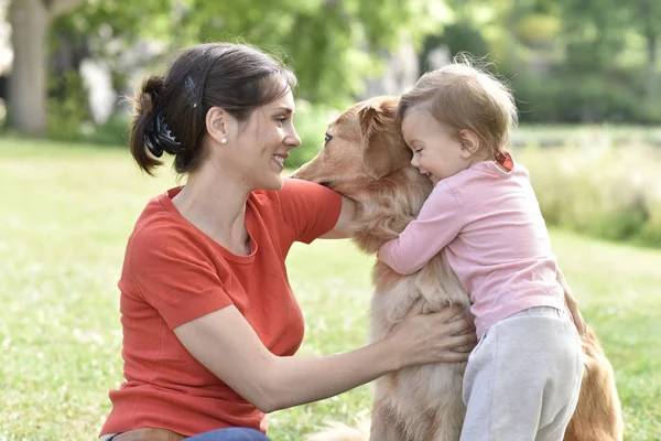 Woman and baby girl hugging dog — Stock Photo, Image