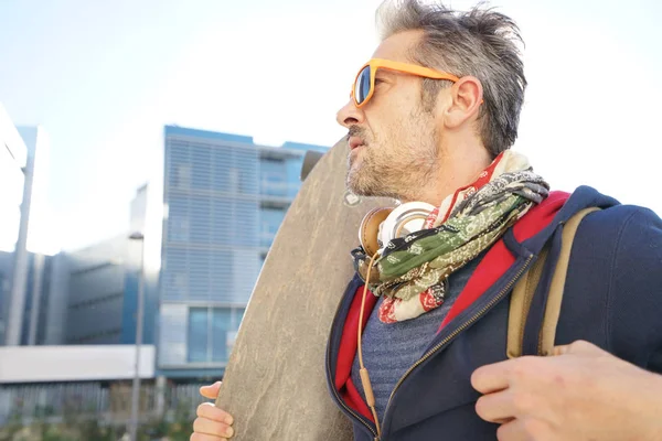 Skateboarder in town holding skateboard — Stock Photo, Image