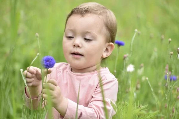 Menina jogando no campo de flores selvagens — Fotografia de Stock