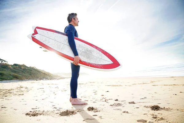 Surfista na praia segurando prancha — Fotografia de Stock