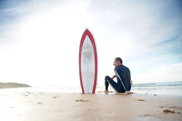Surfista sentado en la playa de arena —  Fotos de Stock