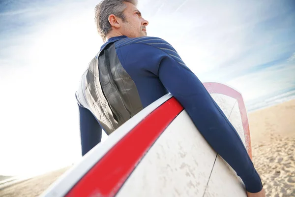 Surfista na praia segurando prancha — Fotografia de Stock