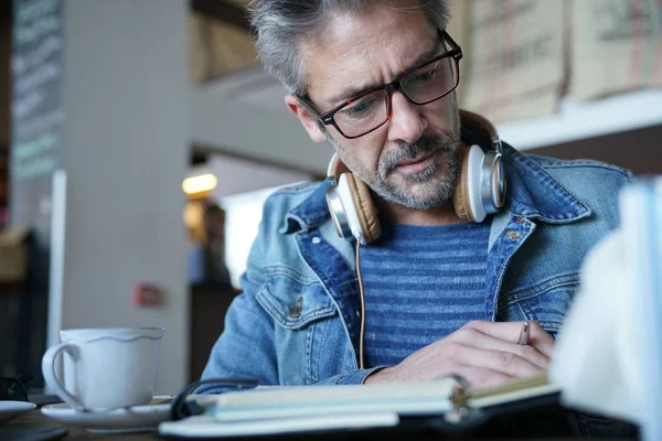 Hombre maduro en la cafetería escribiendo notas — Foto de Stock