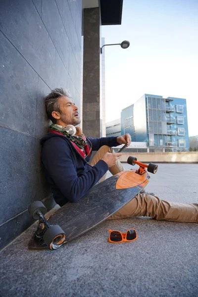 Skateboardista pomocí smartphonu — Stock fotografie