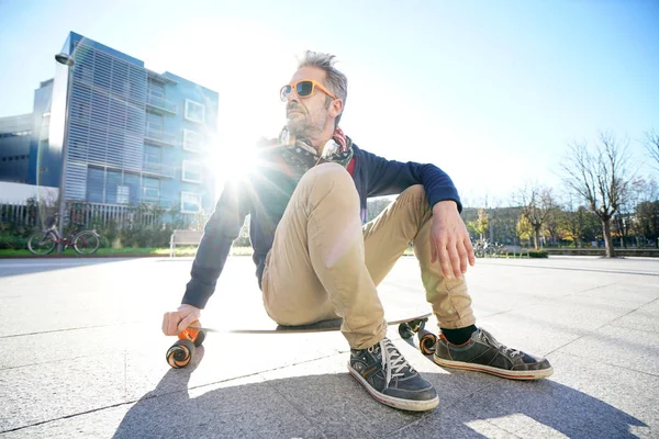 Chlapík sedí na skateboardu v parku — Stock fotografie