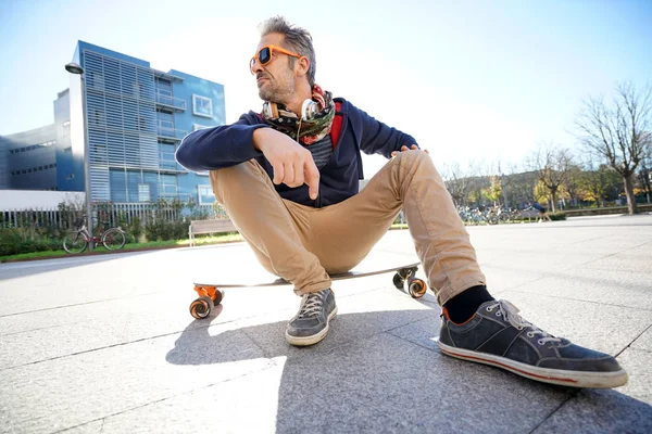 Guy sitting on skateboard in park — Stock Photo, Image