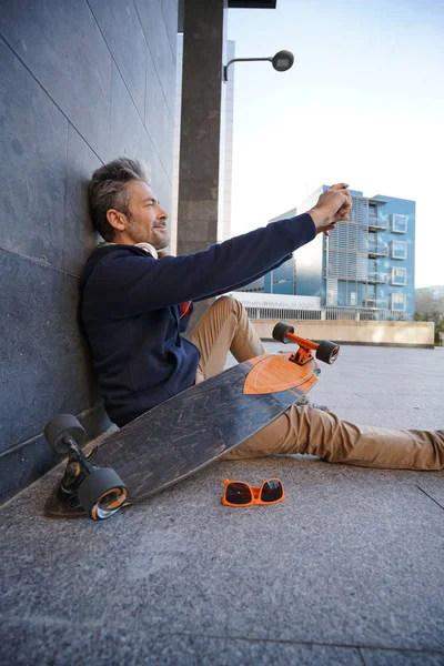 Skateboarder χρησιμοποιώντας smartphone — Φωτογραφία Αρχείου