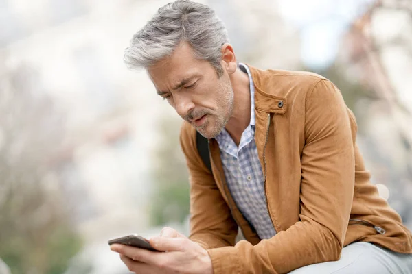 Mature man in town sending message — Stock Photo, Image