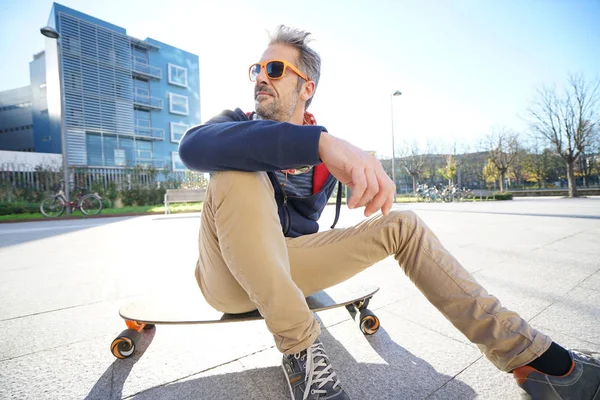 Guy sitting on skateboard in park — Stock Photo, Image