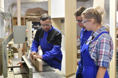 Atölyede çırakları olan marangoz.