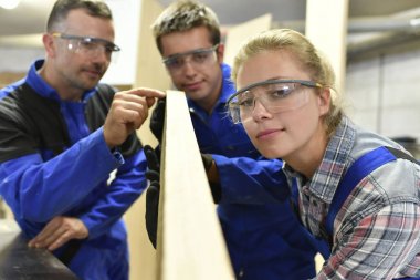 Carpenter with apprentices  in workshop clipart