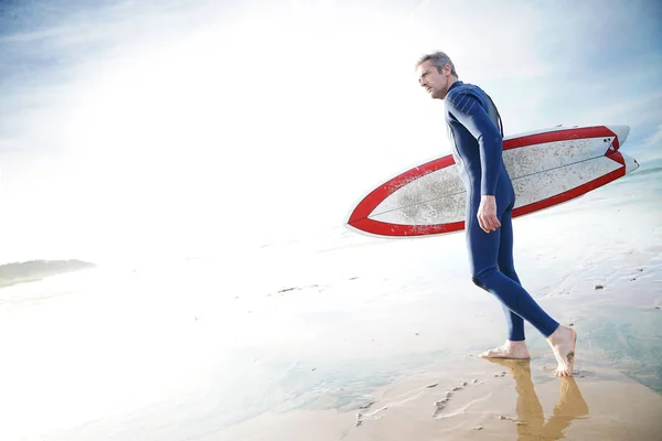 Surfista en la playa sosteniendo tabla de surf — Foto de Stock