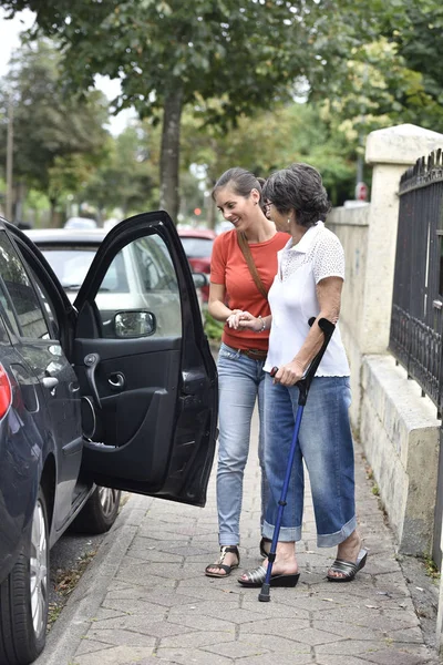 Carer helping  woman getting in car — Stock Photo, Image