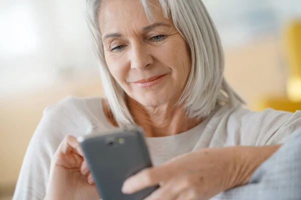 Mulher no sofá usando smartphone — Fotografia de Stock