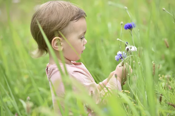 Menina jogando no campo de flores selvagens — Fotografia de Stock