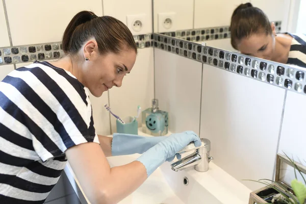 Frau reinigt Wasserhahn im Bad — Stockfoto