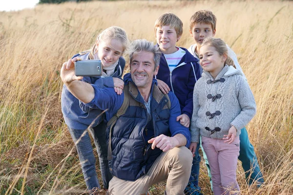 Mann mit Kindern auf Feld macht Selfie — Stockfoto