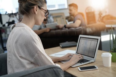 Dizüstü bilgisayarda çalışan genç bir kadın. 