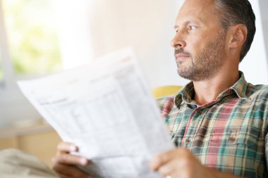 Evde gazete okuyan bir adam.