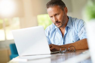 dizüstü bilgisayarda çalışan olgun adam 