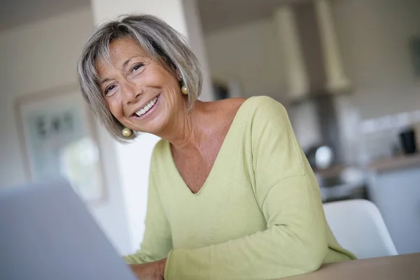Evde kadın kıdemli dizüstü bilgisayar kullanarak — Stok fotoğraf