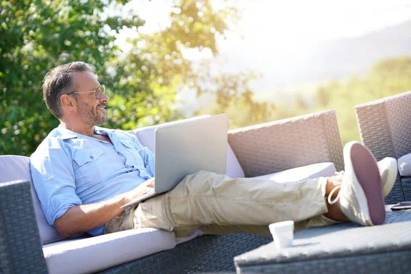 Lachende volwassen man met laptop — Stockfoto