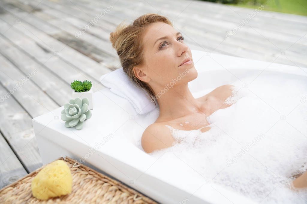 woman relaxing in outdoor bathtub
