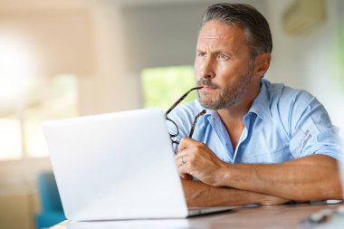 dizüstü bilgisayarda çalışan olgun adam 