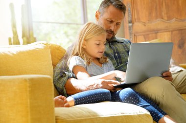 Dizüstü bilgisayar kullanan küçük kız ile baba