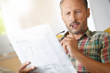 Evde gazete okuyan bir adam.