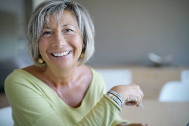 Evde kadın kıdemli dizüstü bilgisayar kullanarak