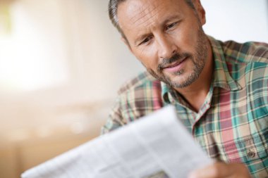 Evde gazete okuyan bir adam.