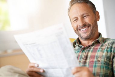 Evde gazete okuyan bir adam.