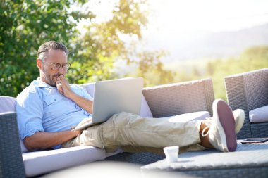 dizüstü bilgisayar kullanan gülümseyen olgun adam