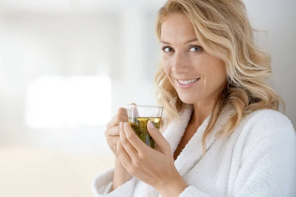Woman in bathrobe drinking infusion — Stock Photo, Image