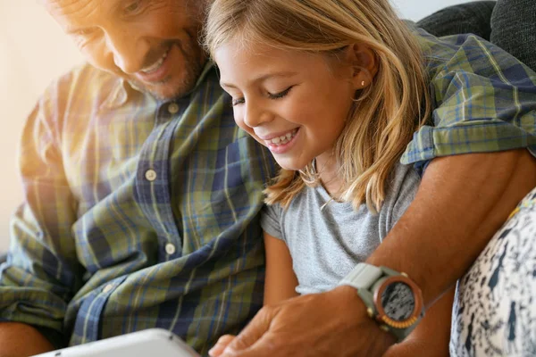 Тато з дівчиною, підключеною на планшеті — стокове фото