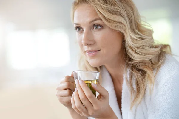 Woman in bathrobe drinking infusion — Stock Photo, Image