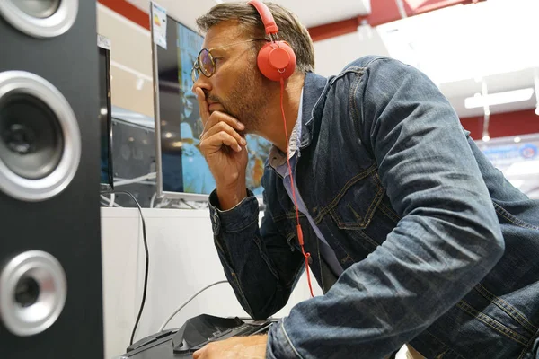 Man in multimedia store testing music with headphones