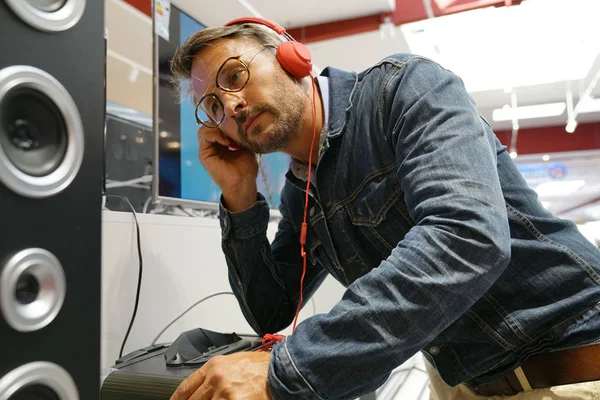 Man in multimedia store testing music with headphones