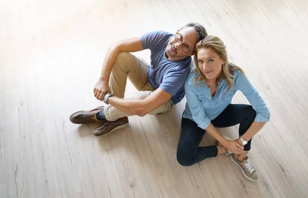 Upper view of couple sitting on wooden floor at home