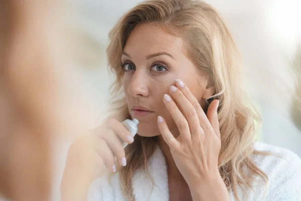 Mujer aplicando crema antienvejecimiento —  Fotos de Stock